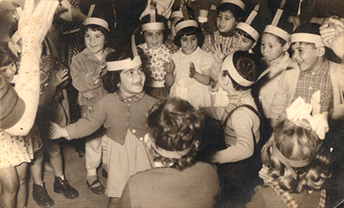 Hanukah in Tehila Kindergarten, Musrara, Varda Amos clapping hands in the center, 1957